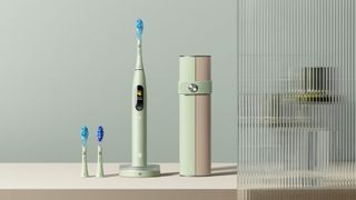 A sage green Oclean X Ultra S toothbrush with extra brush heads and case on a countertop