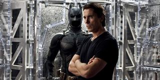 Christian Bale as Bruce Wayne in front of Batman costume in The Dark Knight Rises