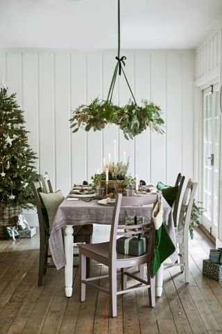 A Christmas-themed dining table set with garland suspended over ceiling and wooden floorboard