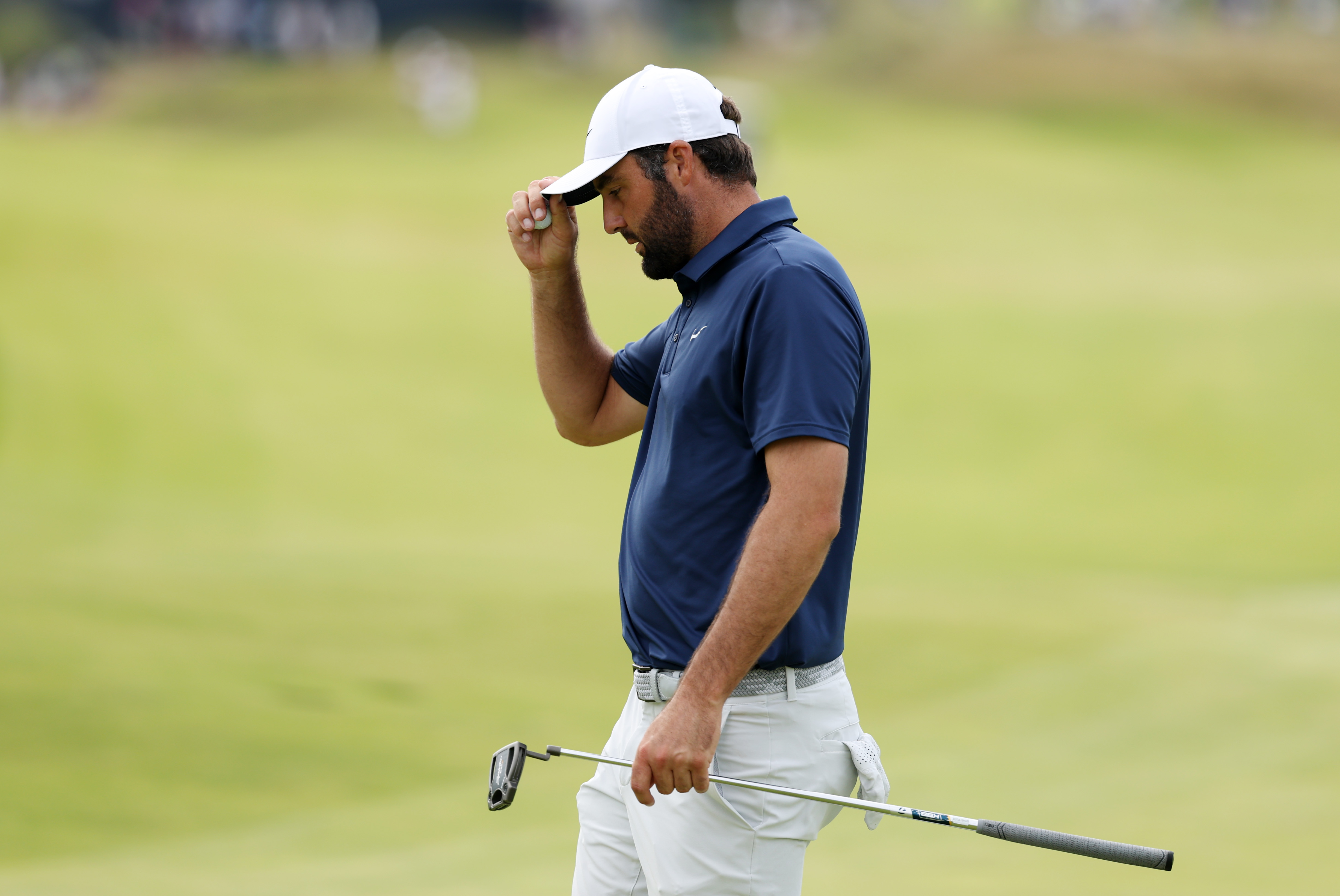 Scottie Scheffler touches his cap as he walks off the green