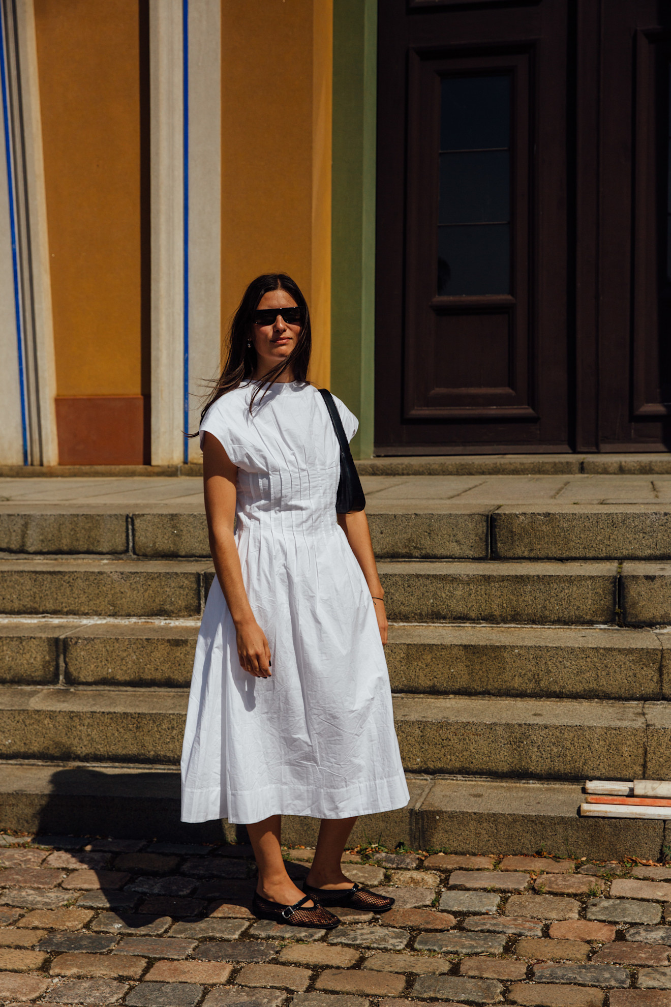 woman wearing white dress, ballet flats, and back purse