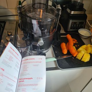 Nutribullet juicer with recipe book and chopped veg next on a chopping board