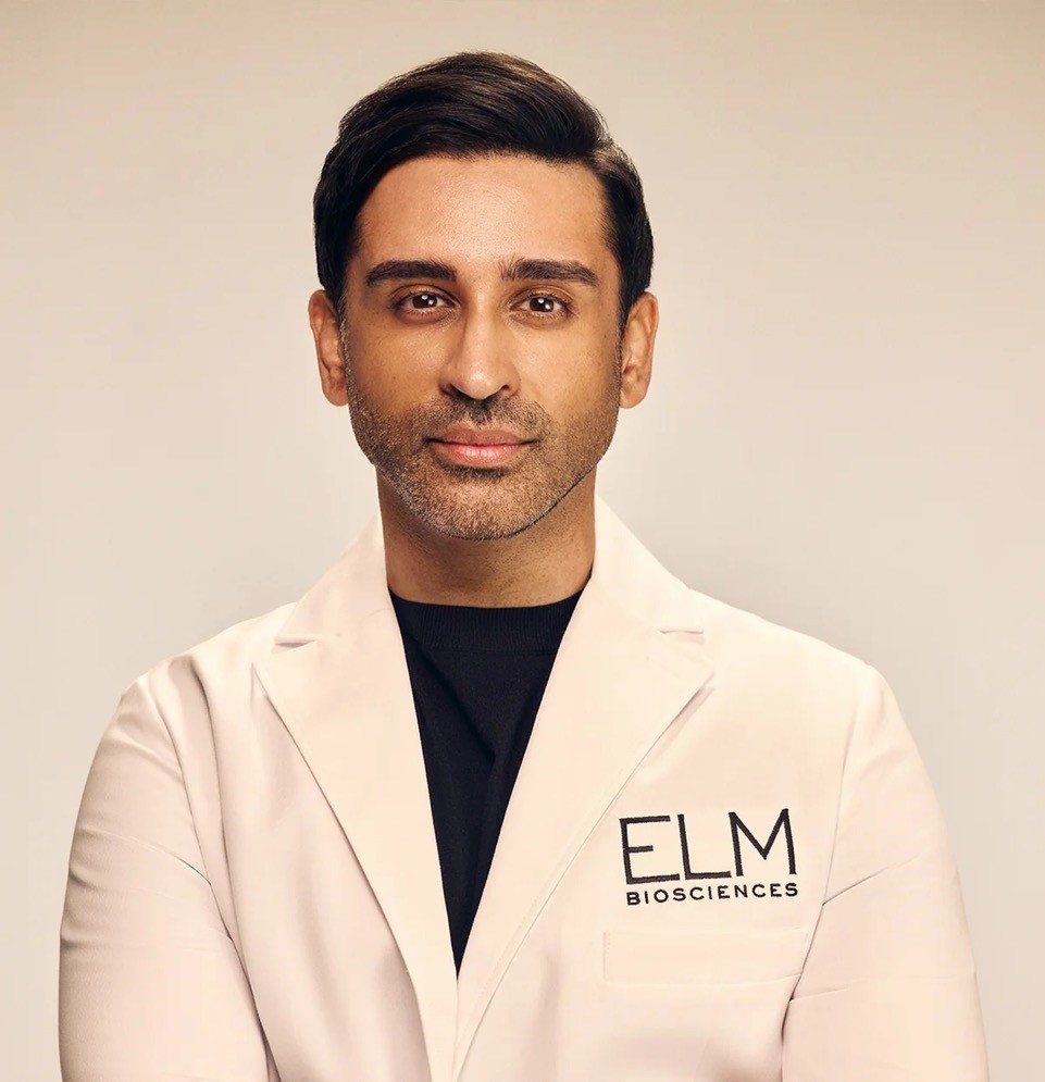 a man with tan skin and dark hair in a white lab coat