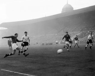 Hungarian centre-forward Nandor Hidegkuti (1922 - 2002) scores his team's 6th goal in the match against England at Wembley, 25th November 1953. England player Jimmy Dickinson (1925 - 1982) is also visible. Hungary won the match 6-3.