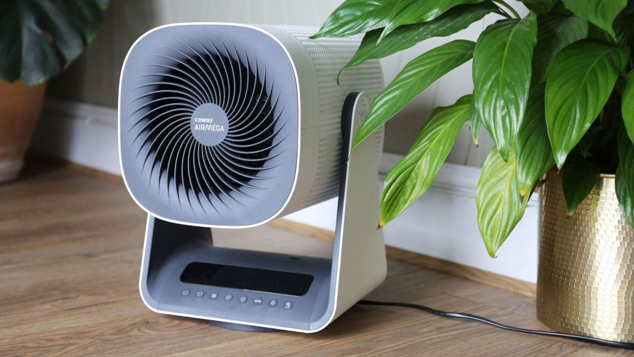 A Coway Airmega Aim Air Purifier beside a potted houseplant