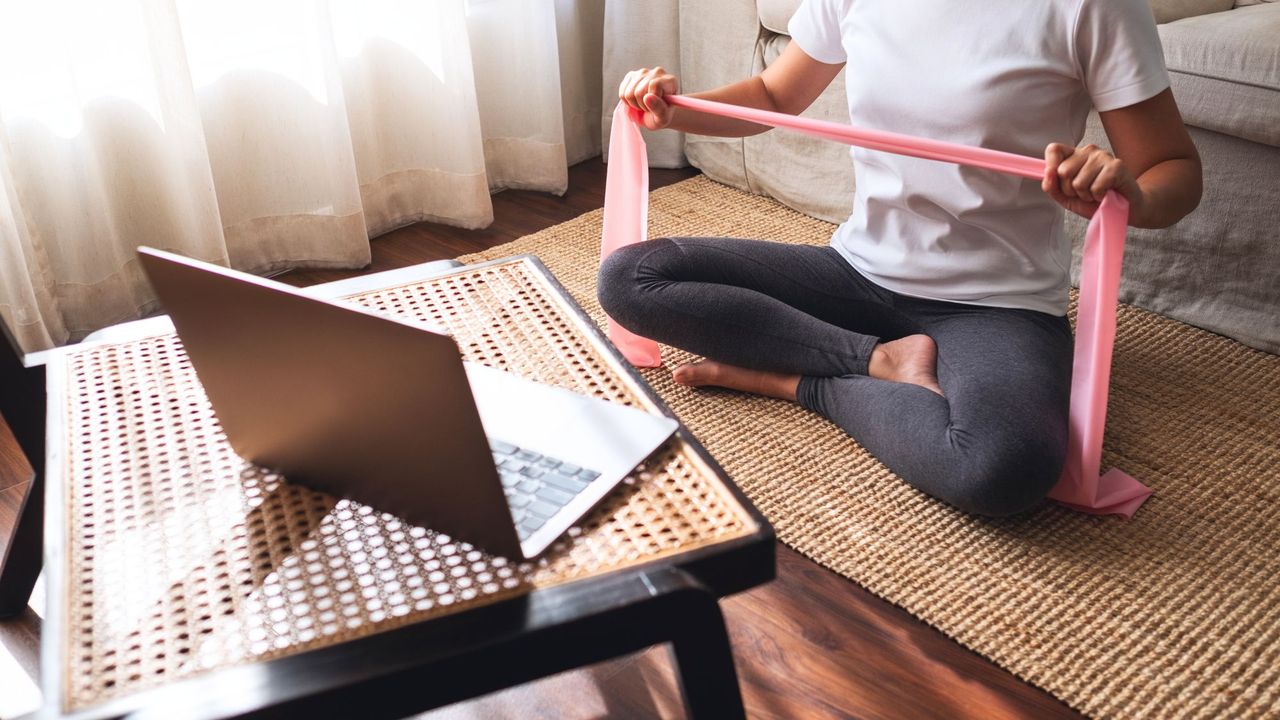 A woman doing a Pilates band workout at home