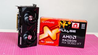 An AMD Radeon RX 9060 XT next to its retail packaging on a table