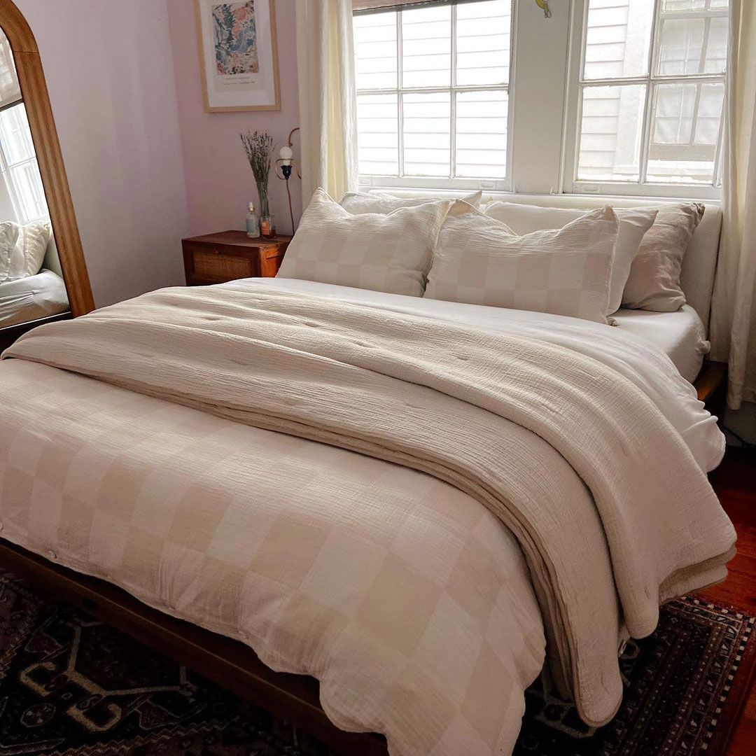 Tempat tidur berpakaian netral di kamar tidur lilac kecil dengan cermin rotan panjang penuh