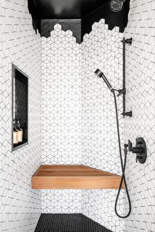 A bathroom with a wooden shower bench and graphic wall tiles