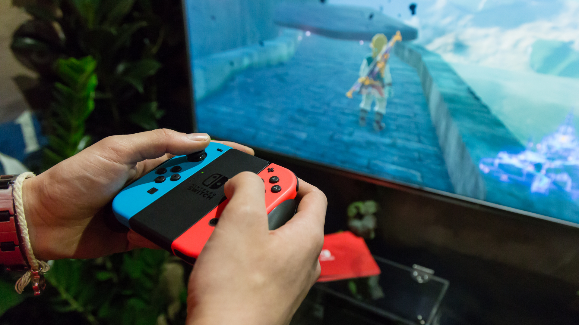 A Игрок Nintendo Switch, использующий контроллеры Joy-Con для игры в Breath of the Wild на телевизоре