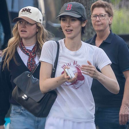 Gracie wears a baseball cap, white graphic tee, and a black chanel bag.