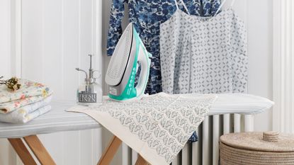 Steam iron placed on top of ironing board with tea towels