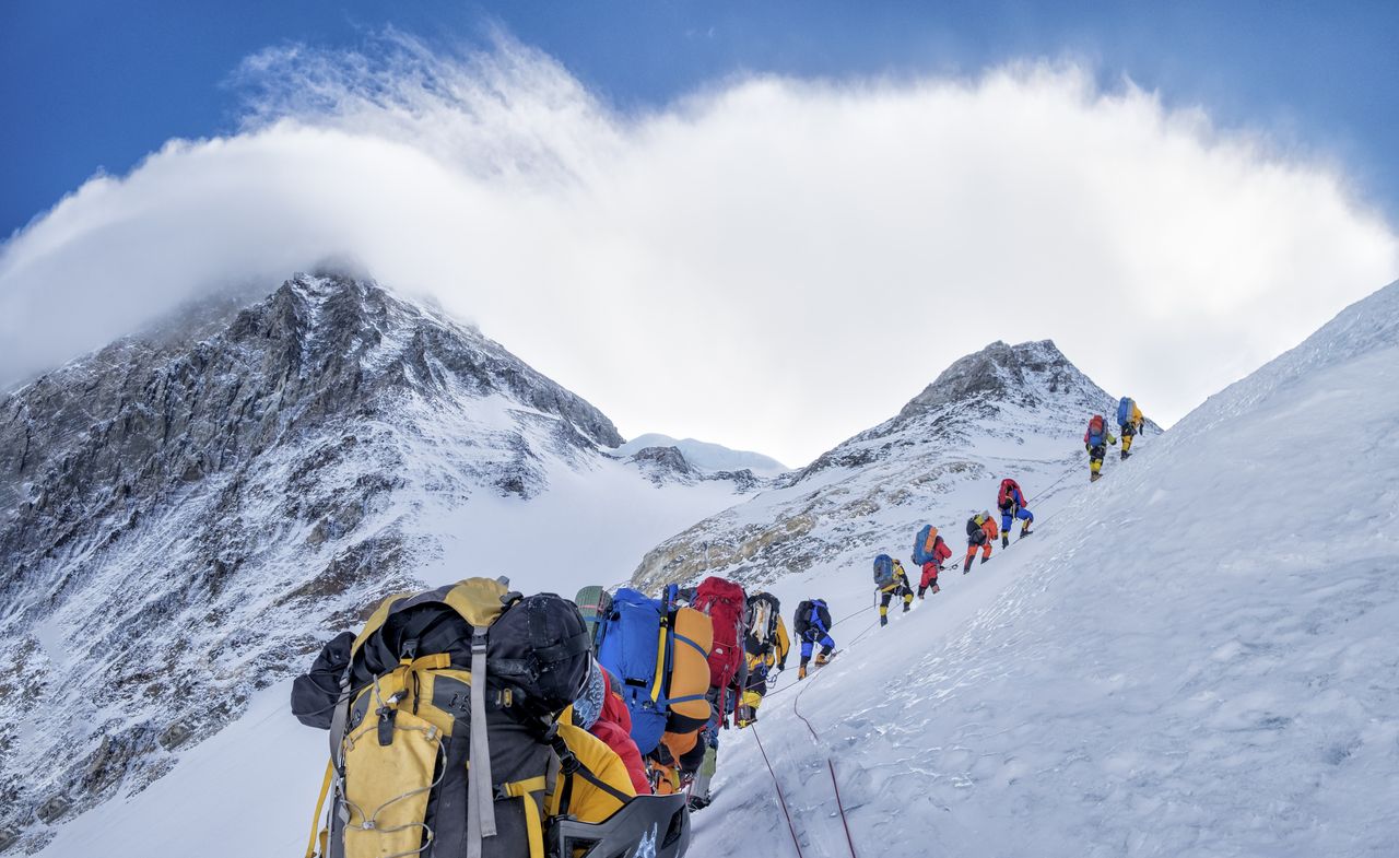 A group of climbers ascends Everest wearing colorful gear.