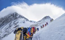 A group of climbers ascends Everest wearing colorful gear.