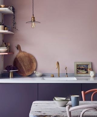 kitchen with purple cabinets, pink wall, white countertops with brass fixtures