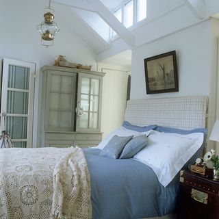 white bedroom with blue bed linen neutral headboard and grey storage cupboards