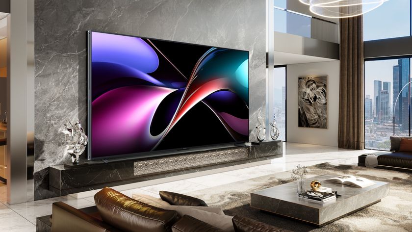 A 116-inch TV displaying a colorful, abstract pattern in front of a marble wall in a large, upscale living space overlooking a cityscape