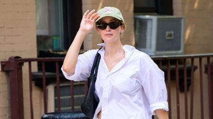 Jennifer Lawrence wearing an all white outfit with a pair of multicolored New Balance x Aimé Leon Dore sneakers in New York City July 2024