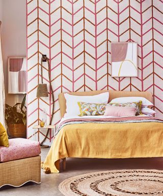 A colorful bedroom with patterned wallpaper and a yellow bed.