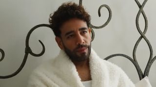 Mido laying in bed in a robe. 