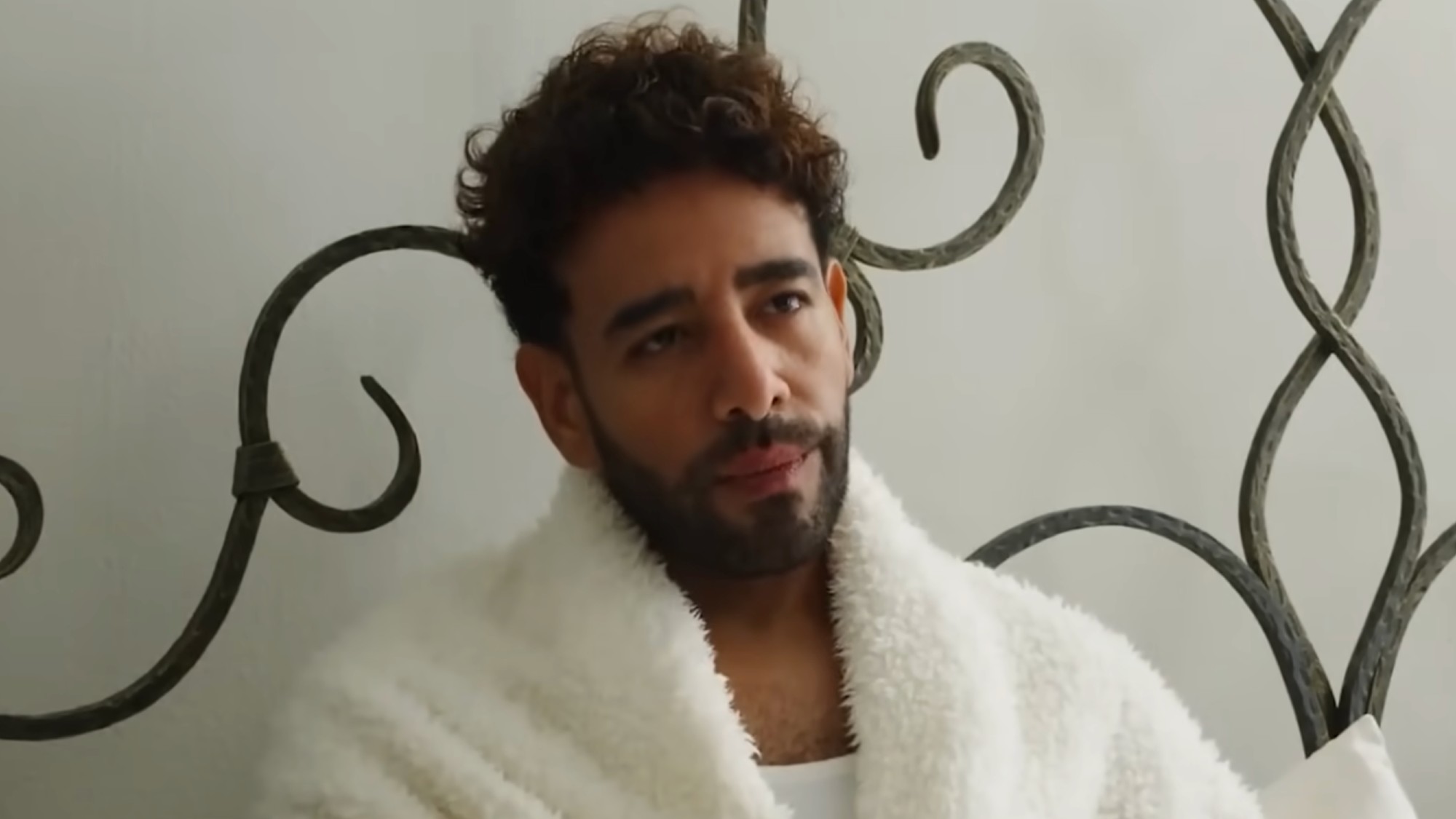 Mido laying in bed in a robe. 