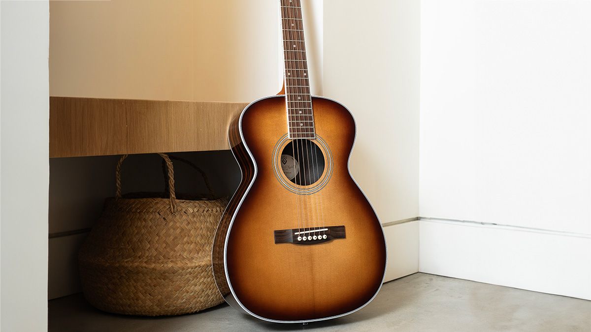 A photo of the Guild M-260E Deluxe Archback acoustic guitar against a white background in a room setting