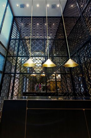 Custom brass pendants complement the inlay cut across towering wrought-iron panels in the reception area