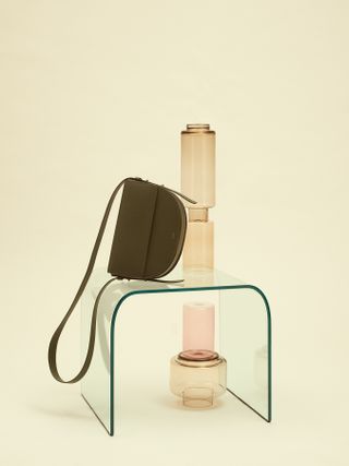 Green leather bag lies on a glass table