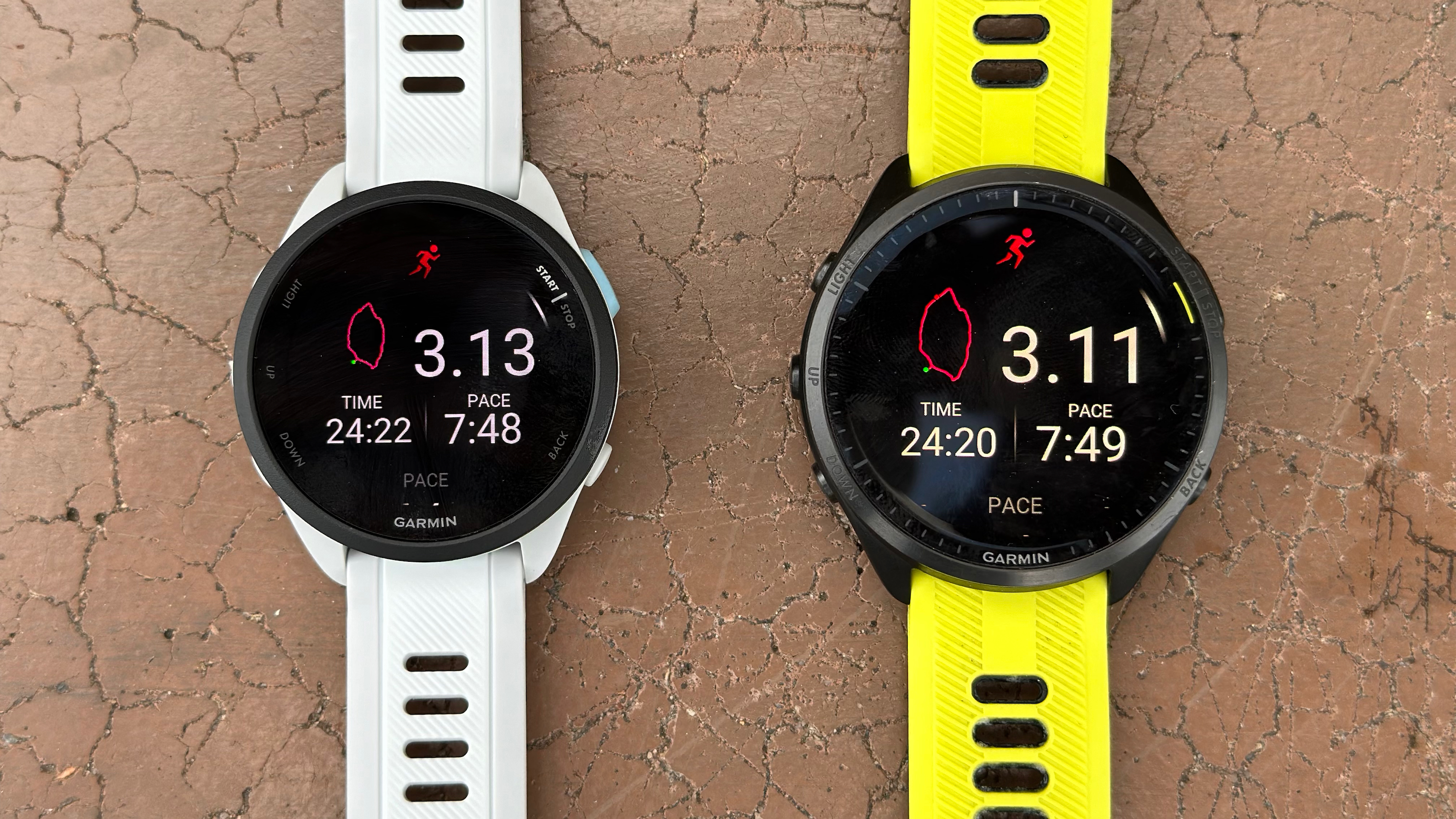 The Garmin Forerunner 165 and 965 side-by-side on a bench, showing near-identical distance and pace after a run activity.