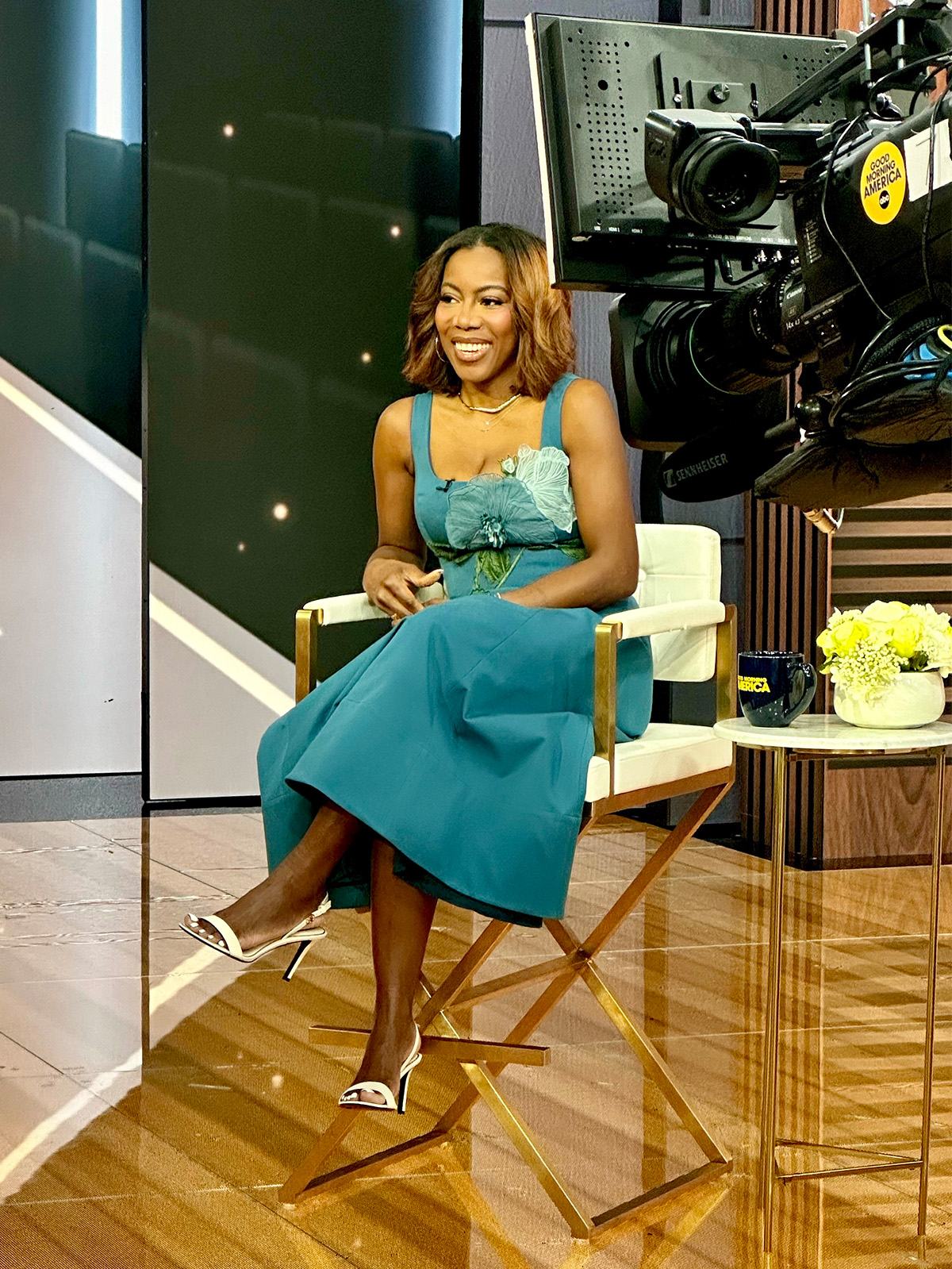 Who What Wear Editor in Residence Tiffany Reid wearing a blue dress with floral appliqu&amp;egrave;s for a TV segment.