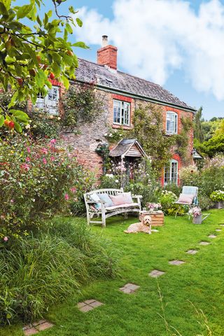 Georgian cottage home with cottage garden and wooden bench and dog