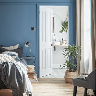 bedroom with blue pale wall and wooden floor and white door
