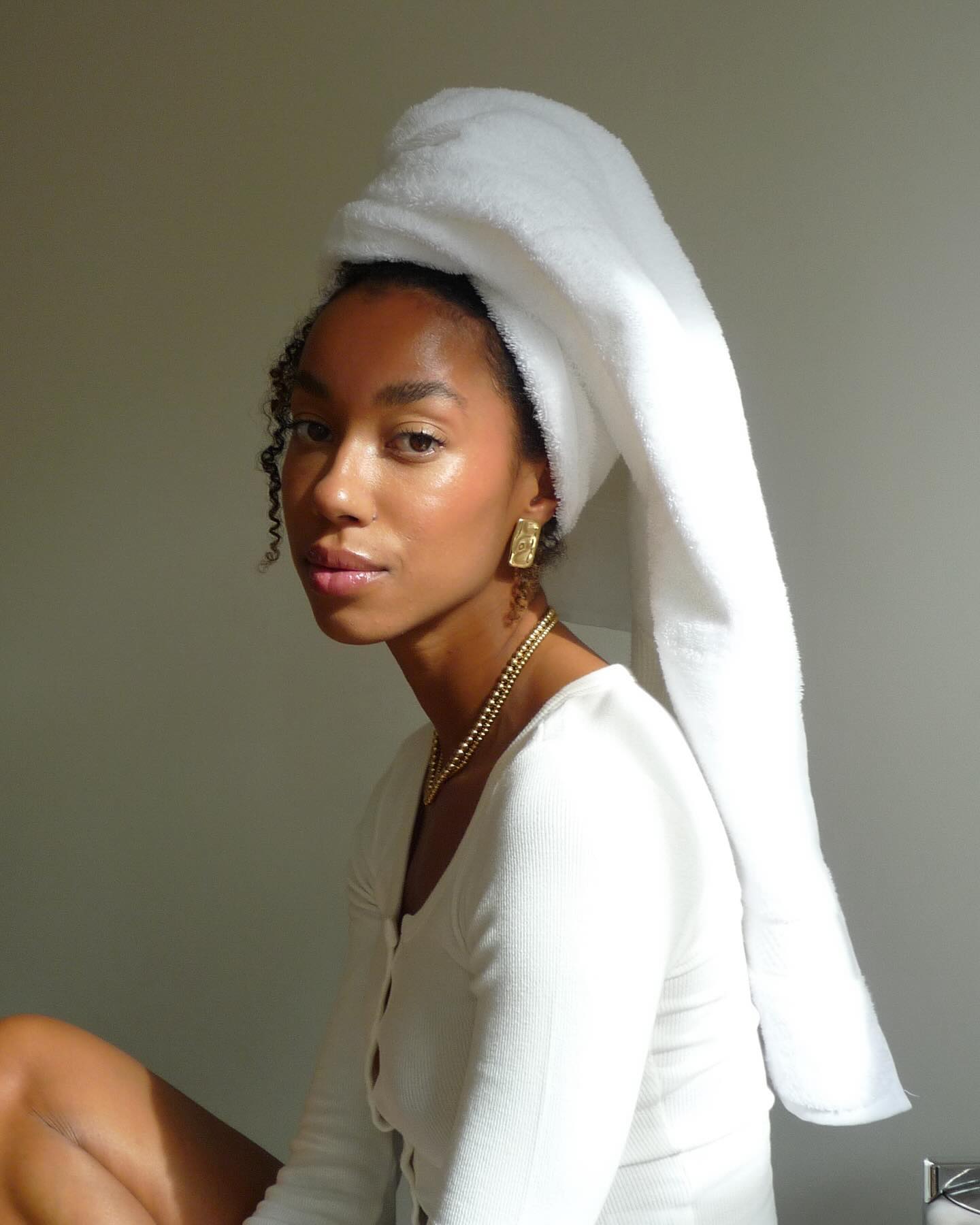 Amaka wearing white head towel with gold jewellery and white buttondown top