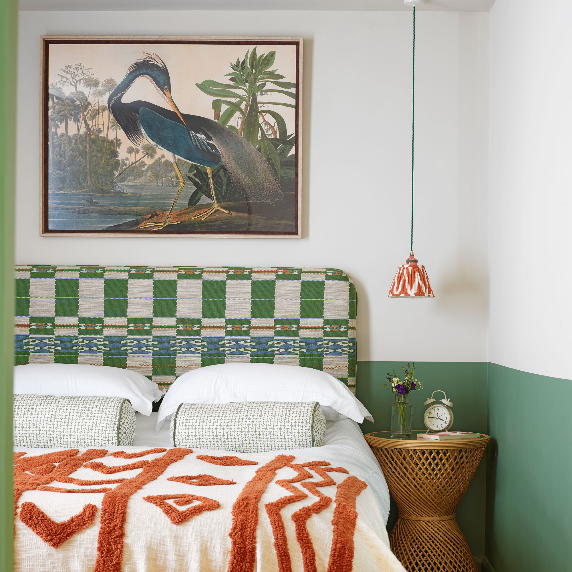 Green and white bedroom with green pattern headboard and heron picture above bed.