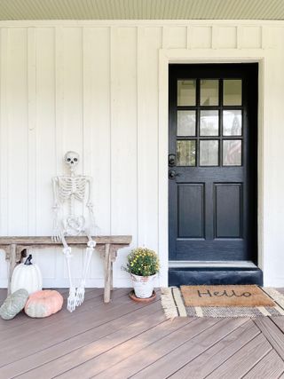 White paneled front porch with Halloween skeleton