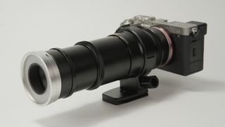 Close-up of a Sony Alpha 7C mirrorless camera with a long, black telephoto lens attached, showcasing its detailed design