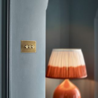 Close up of a brass dimmer switch on a blue wall