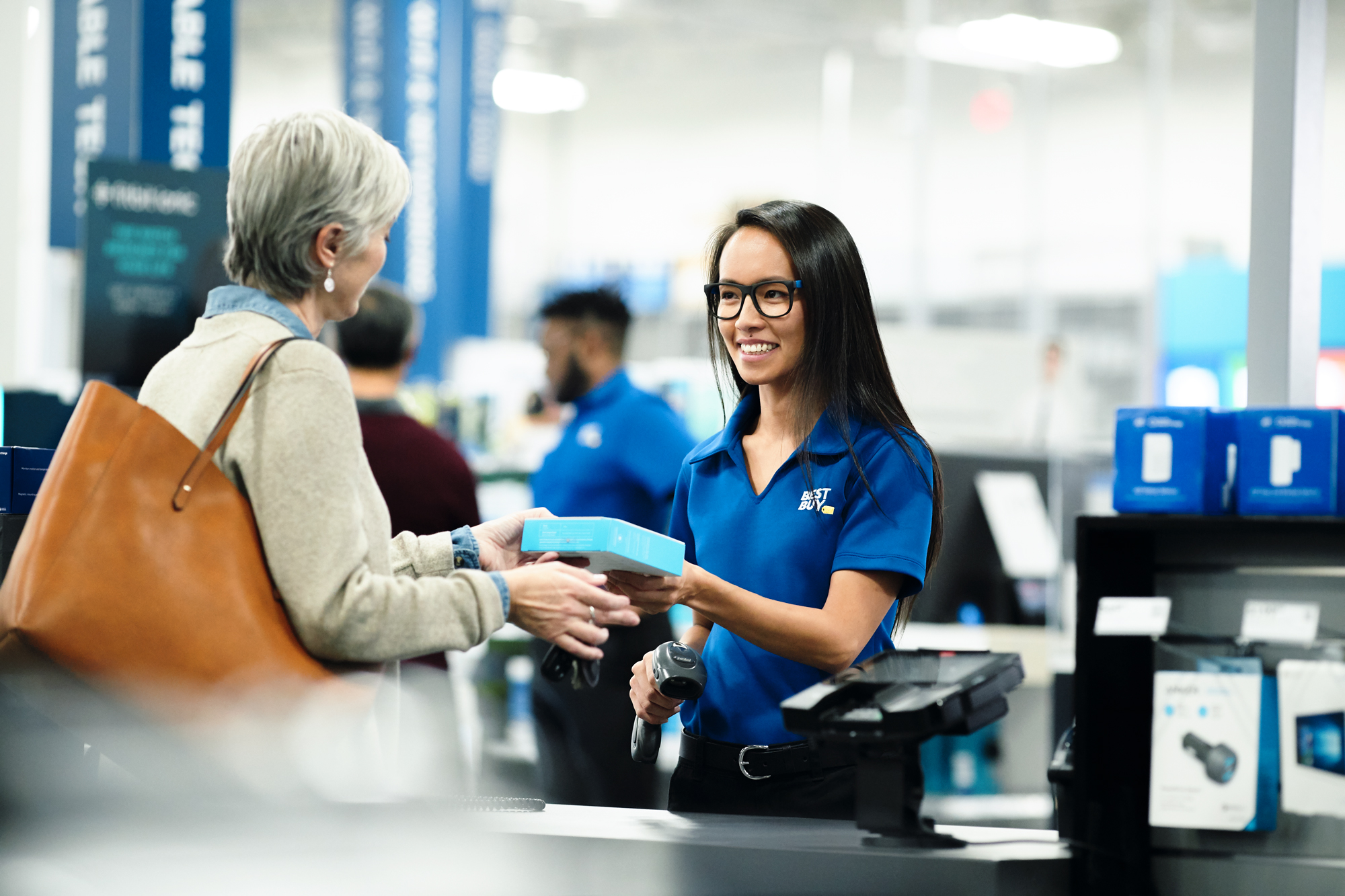 A Best Buy employee assists a senior customer with a purchase in store. 