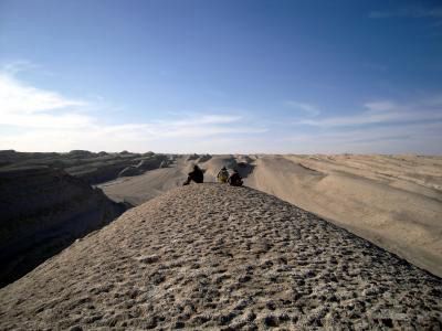 Researchers sit atop a wind-formed ridge in Central Asia.