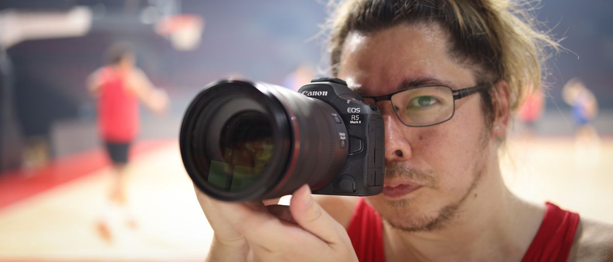 Photographer James Artaius using a Canon EOS R5 Mark II in front of a basketball game