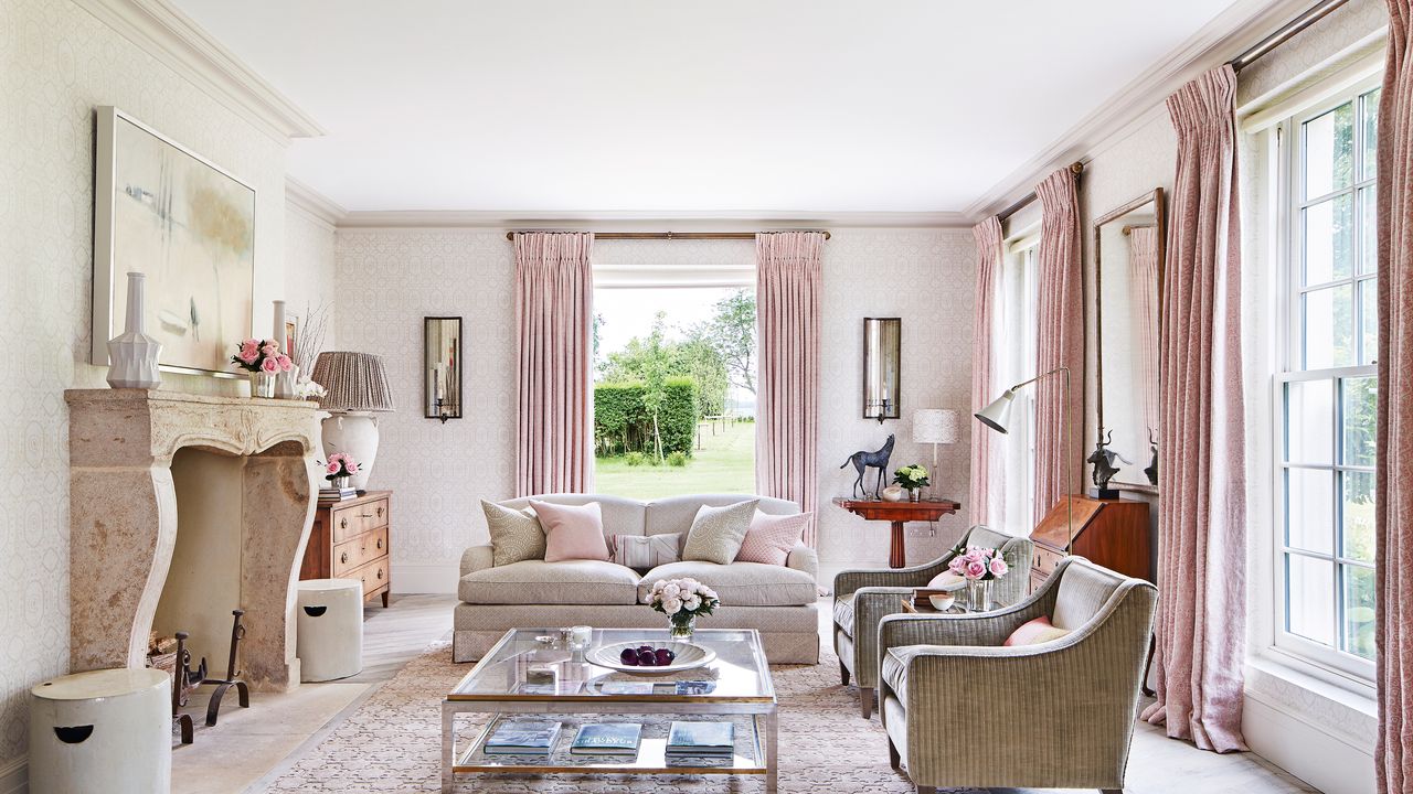 A light pink living room with large windows and ornate fireplace