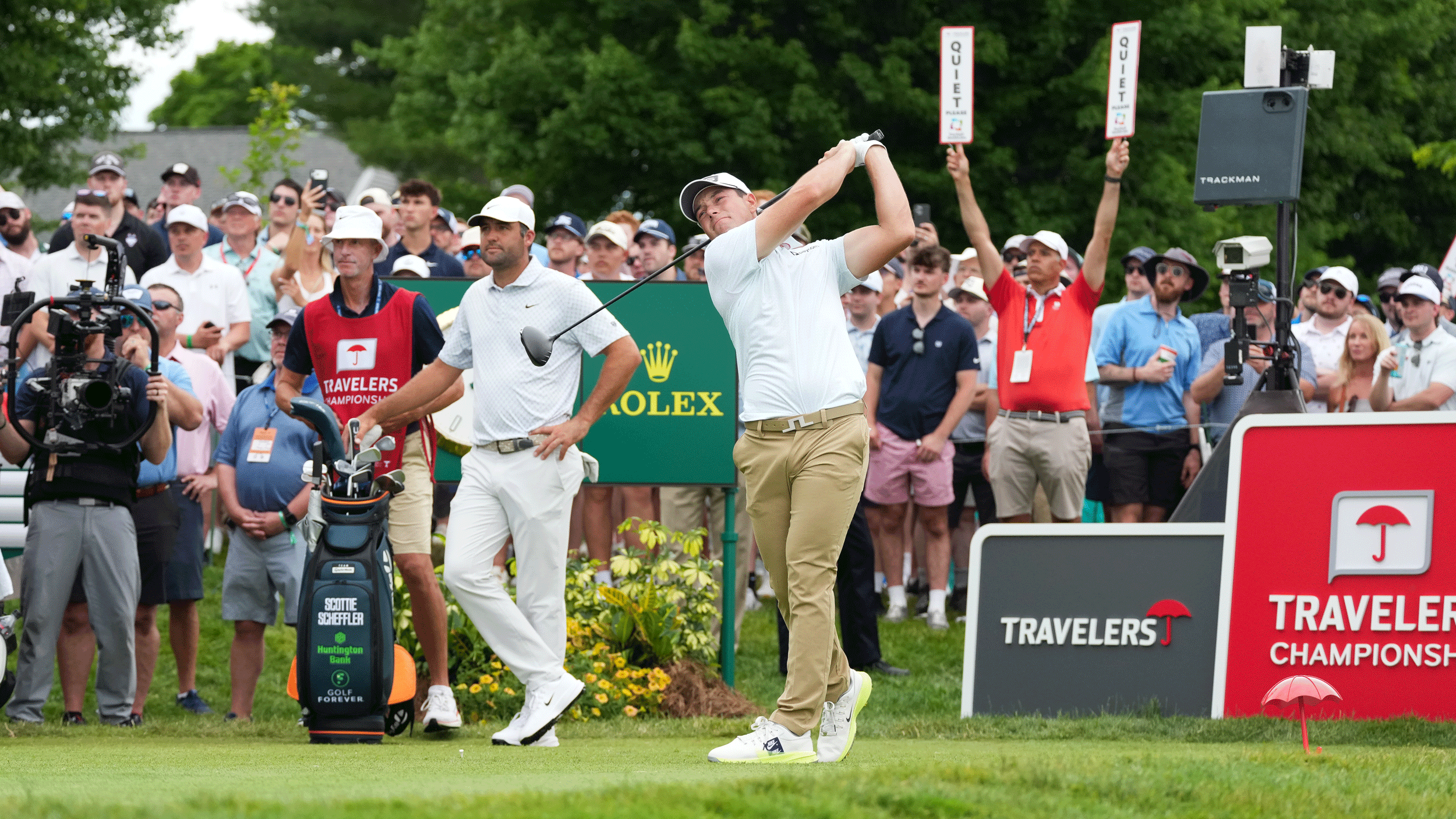 Viktor Hovland hits a drive during round three of the Travelers Championship with Scottie Scheffler and Ted Scott in the background
