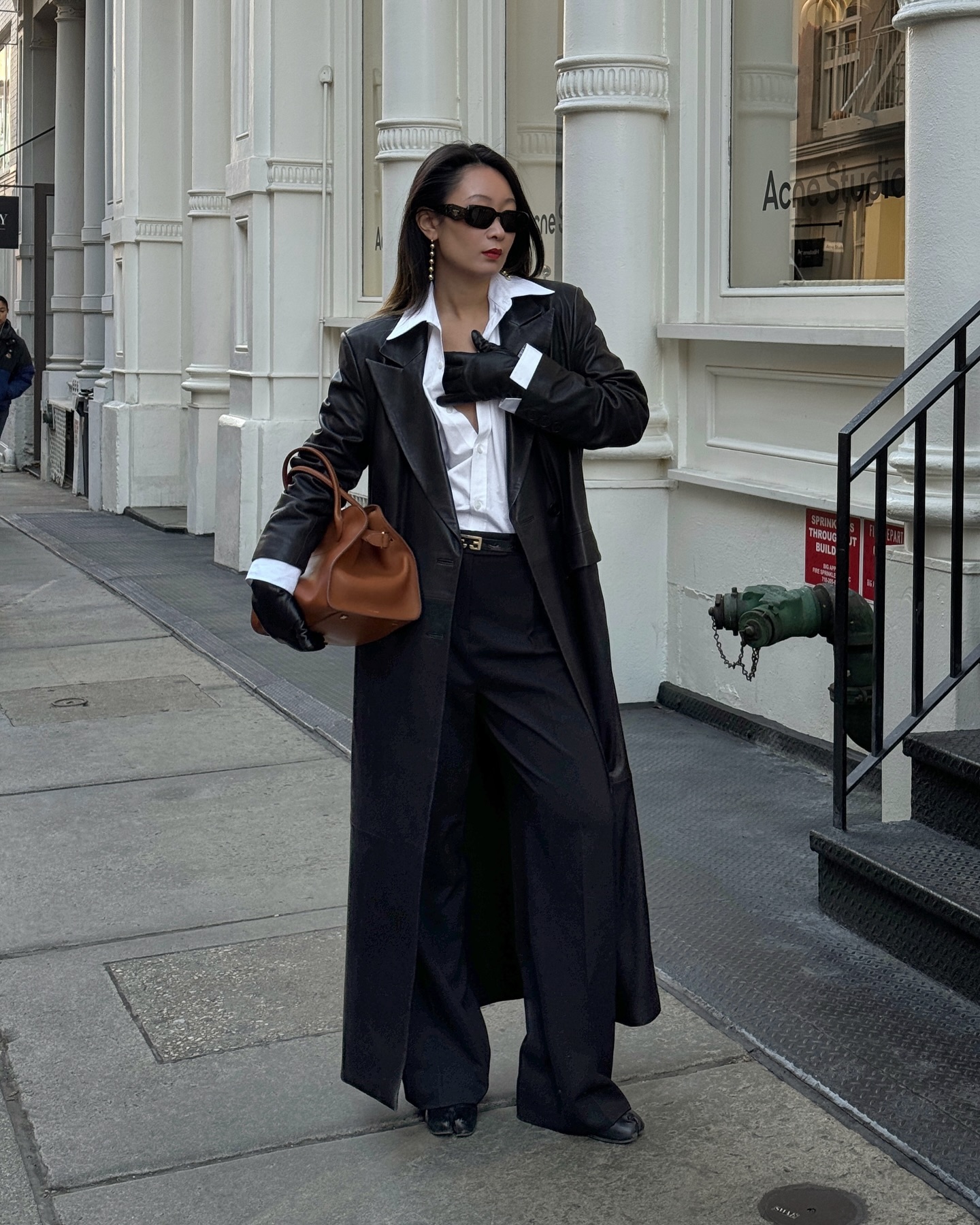 @thecarolinelin wears a black trench coat, white button down, blue jeans and black ballet flats.