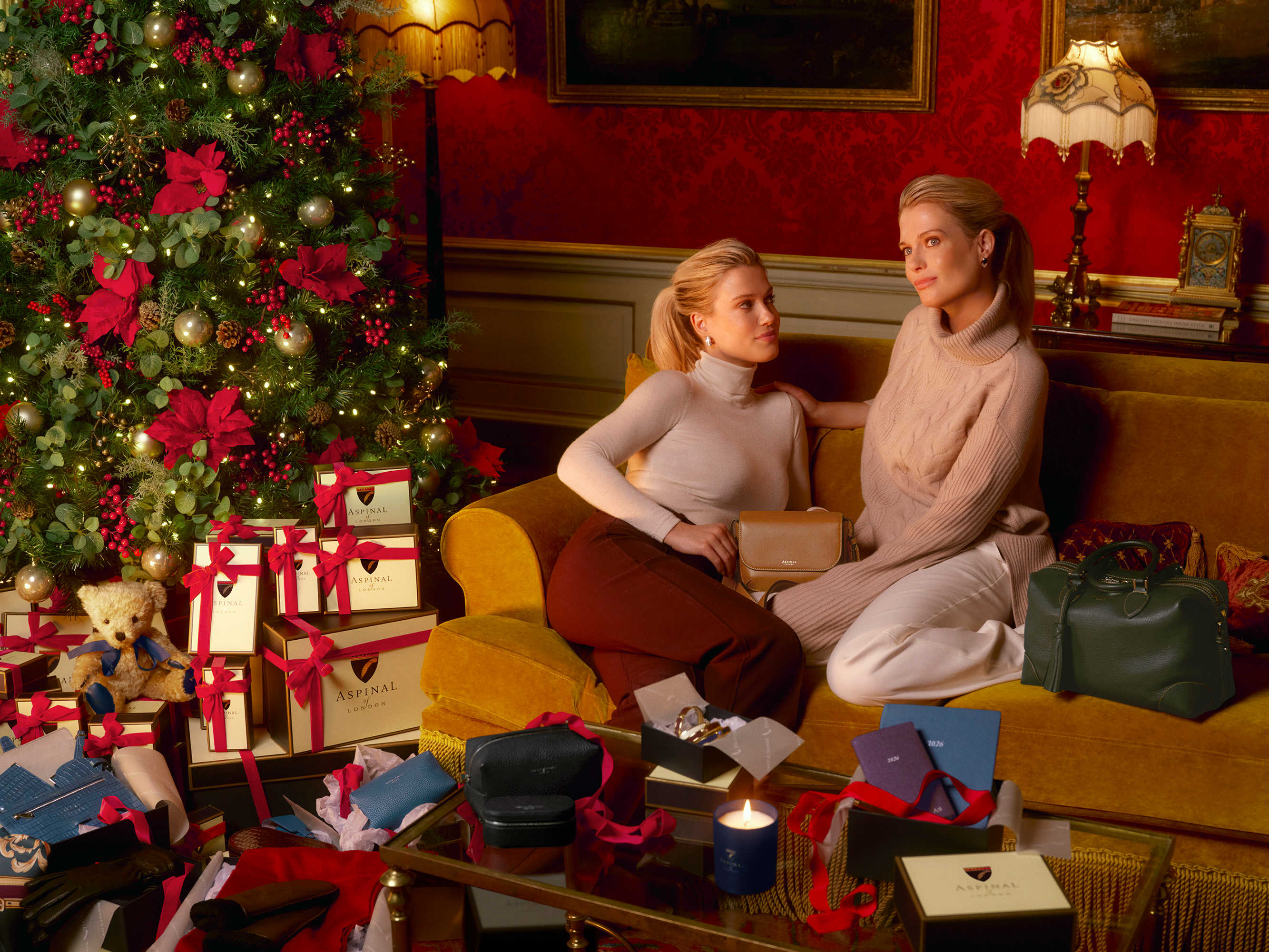 Amelia and Eliza Spencer sitting next to a Christmas tree with gifts