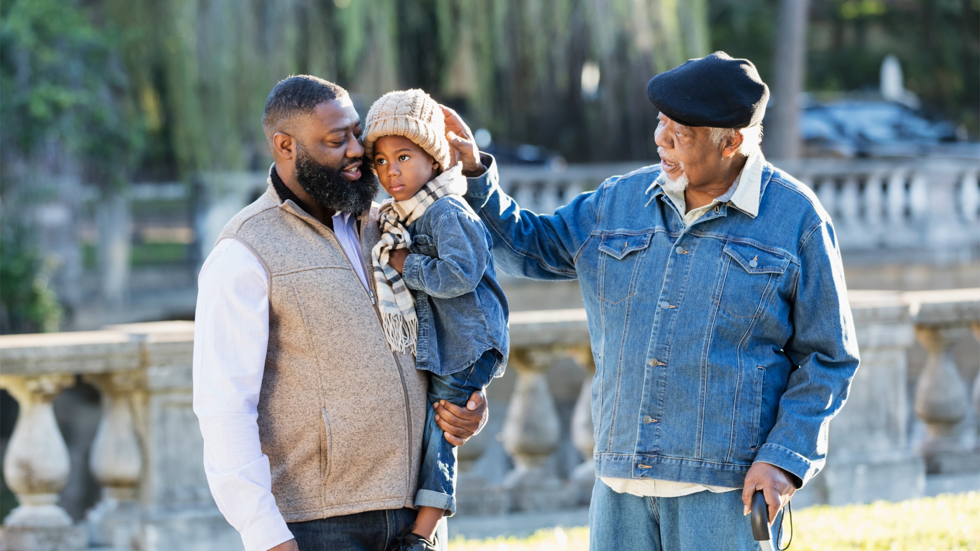 Senior man with his son and grandson taking a walk in the park on a sunny autumn day