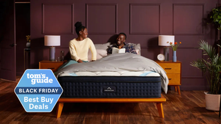 Two people sitting on the Dreamcloud Premier Hybrid in a bright in a chic bedroom 