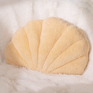 A pastel orange fluffy pillow shaped like a seashell
