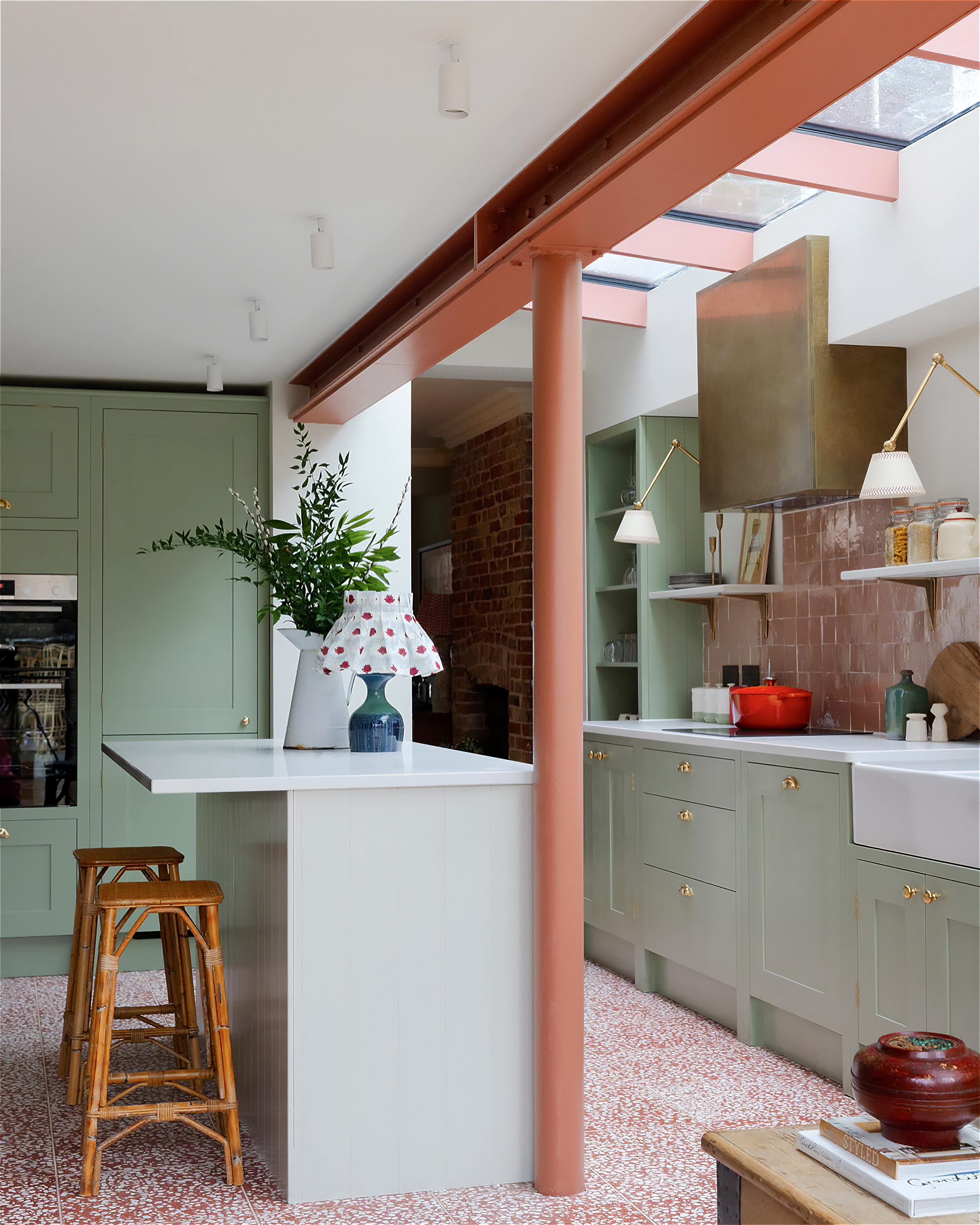 a light green kitchen extension with red terrazzo tile flooring and a white island