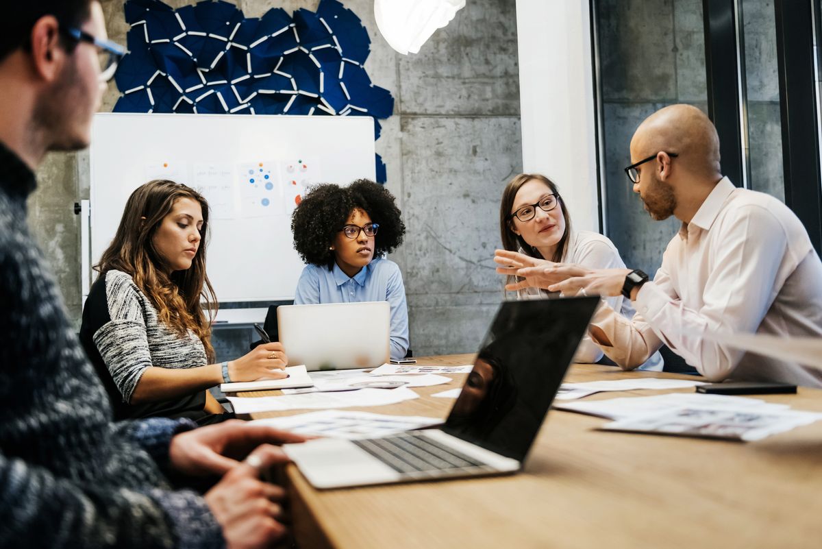 Group of 5 people meeting in an office around a conference table