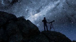 Man and telescope on mountain with stars behind